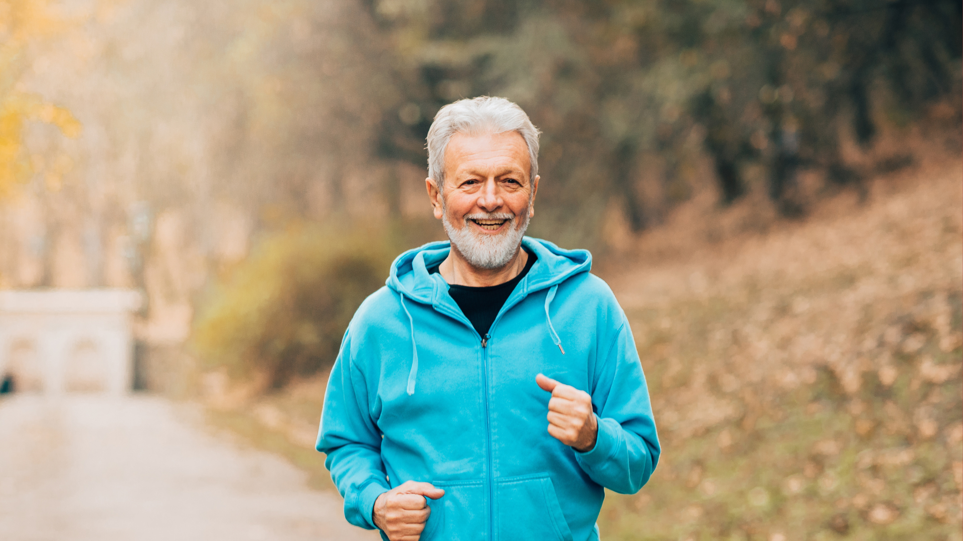 Elderly man jogging happily in a park, symbolizing vitality and wellness.